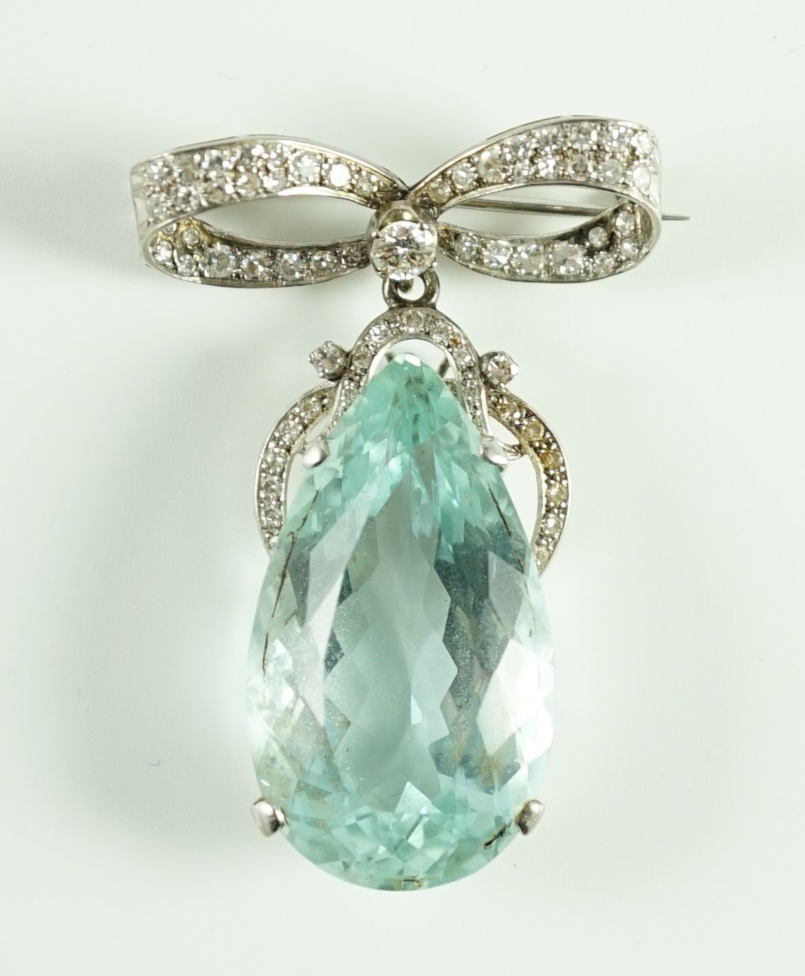 A mid 20th century continental white gold, facet cut pear shaped aquamarine and diamond set drop pendant, on a diamond set ribbon bow brooch